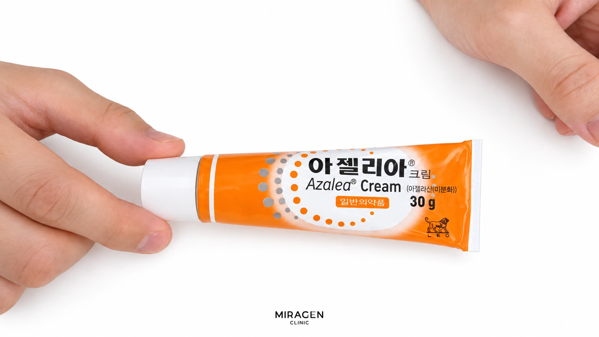 흰 바탕 위에서 손으로 잡고 있는 아젤리아 크림 30g 주황색 튜브